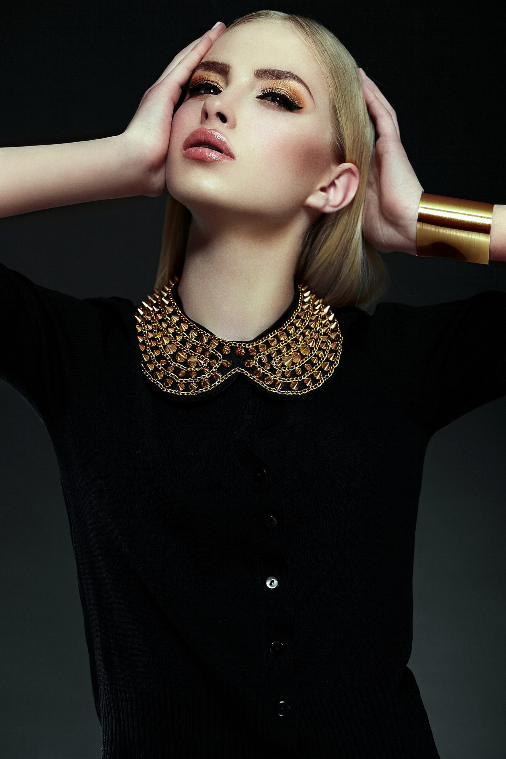 high fashion look.glamor closeup portrait of beautiful sexy stylish blond young woman model with bright yellow makeup with perfect clean skin with gold jewelery in black cloth